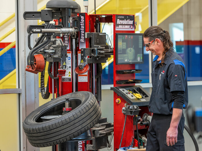 Technician operating the Hunter Revolution semi-autonomous tire changer