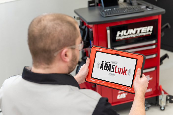 Technicien utilisant la fonction de mise en miroir de l’écran ADASLink pour afficher les mesures de carrossage et de parallélisme vertes et rouges à partir du logiciel WinAlign.